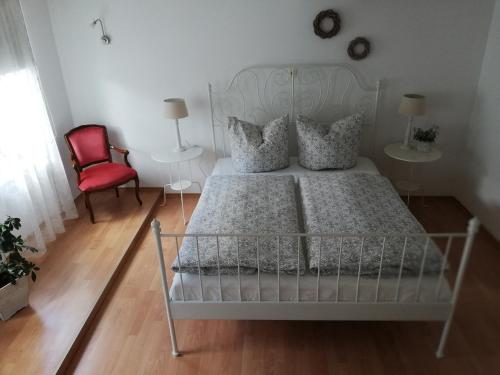 1 dormitorio con 1 cama blanca y 1 silla roja en Ferienwohnung am Töpferplatz, en Höhr-Grenzhausen