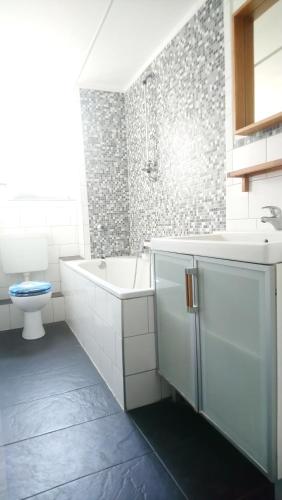a bathroom with a tub and a sink and a toilet at AVI City Apartments BismarckHouse in Düsseldorf