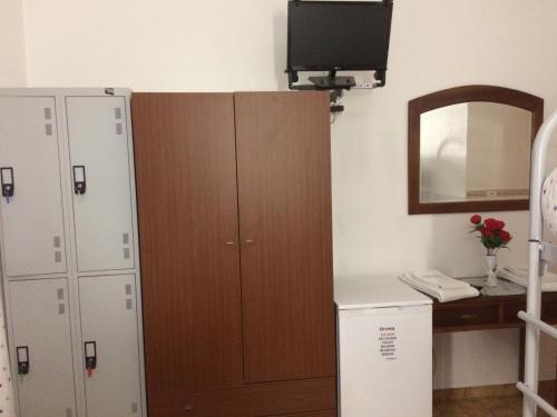a room with a cabinet and a television on a wall at Hostel Boutique Marisol in Monte Gordo