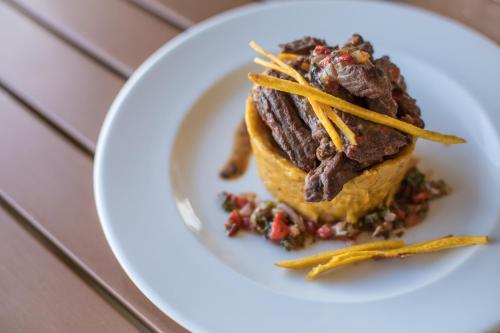 a white plate with a steak sandwich on a table at Ciqala Suites Hotel - San Juan in San Juan