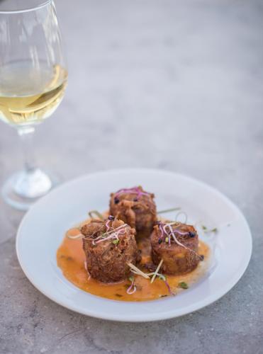 a plate of meatballs with a glass of wine at Ciqala Suites Hotel - San Juan in San Juan