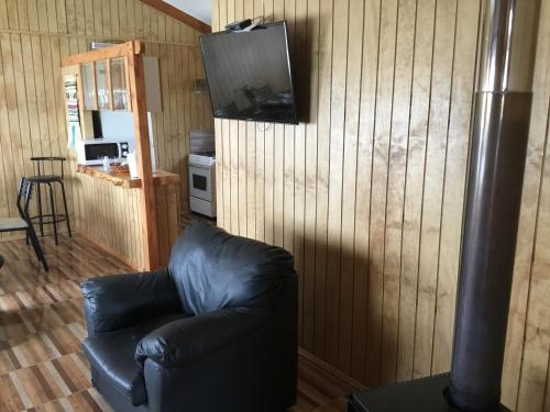 a black leather couch in a living room with a tv on the wall at Cabañas 4 Volcanes Frutillar in Frutillar