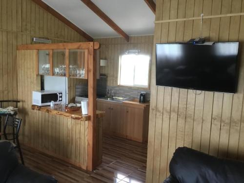 a living room with a television on a wooden wall at Cabañas 4 Volcanes Frutillar in Frutillar