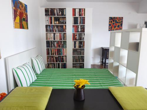 a room with a bed with green sheets and books at Cozy Place in Sintra