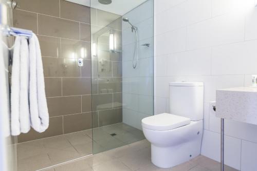 a bathroom with a toilet and a glass shower at Mantra Gladstone in Gladstone