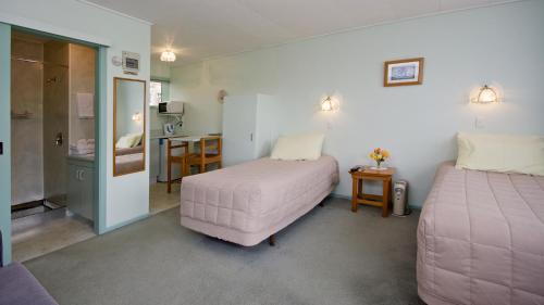 a room with two beds and a table and a kitchen at Owaka Lodge Motel in Owaka