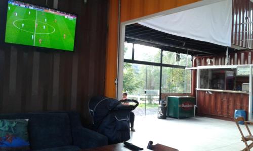 a living room with a couch and a tv on the wall at Pousada Recanto dos Bentos in Itapeva