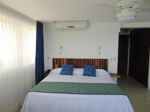 a bedroom with a large bed with blue pillows at Hotel Rosita in Puerto Vallarta