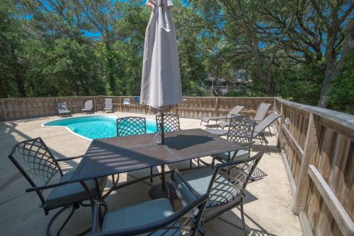 a table with an umbrella and chairs next to a pool at Gone With the Wind in Duck