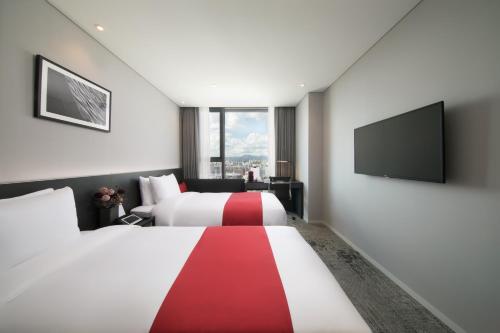 a hotel room with two beds and a flat screen tv at Aiden by Best Western Cheongdam in Seoul