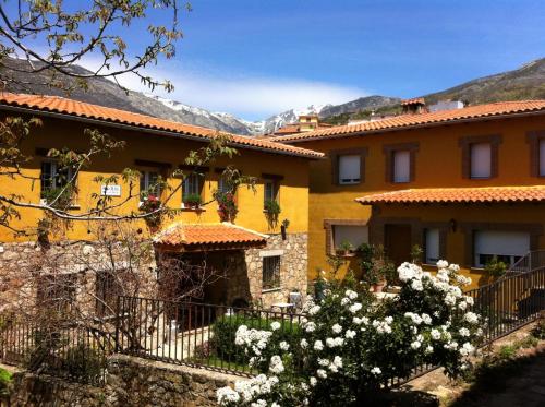 Casa Rural Sierra de Tormantos في Guijo de Santa Bárbara: مبنى اصفر بالورود البيضاء امامه