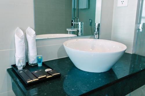 a bathroom with a large white sink and a tub at Sun Bay Tuan Chau Hotel in Ha Long