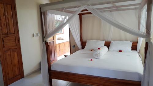 a bedroom with a bed with white sheets and a window at New Starlight Hotel Lovina in Lovina