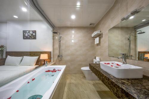 a bathroom with a tub and a bed and a sink at Granda Suites Hanoi in Hanoi