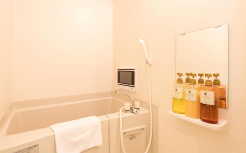 La salle de bains est pourvue d'une baignoire, d'un miroir et de serviettes. dans l'établissement Floral Green Maple House, à Kyoto