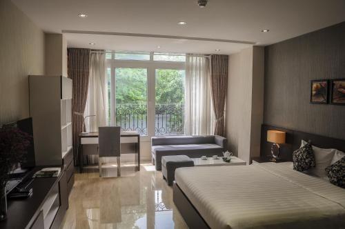 1 dormitorio con 2 camas, escritorio y sofá en Sunny Serviced Apartment, en Ho Chi Minh