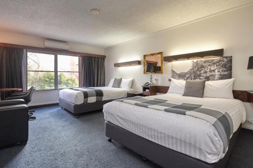 a hotel room with two beds and a window at Quality Hotel Colonial Launceston in Launceston