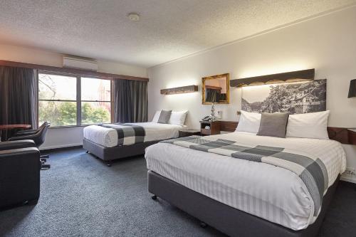 a hotel room with two beds and a window at Quality Hotel Colonial Launceston in Launceston