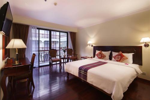 a bedroom with a bed and a desk and a window at Smiling Deluxe Hotel in Siem Reap