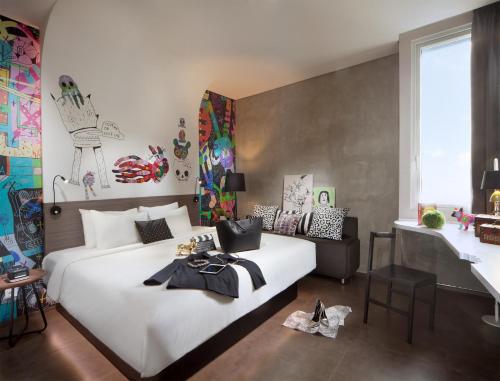 a bedroom with a large white bed and a table at ARTOTEL Thamrin Jakarta in Jakarta