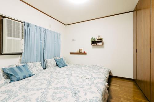 ein Schlafzimmer mit einem Bett mit blauen Kissen in der Unterkunft Kashikiri Ikkenya Sora in Osaka