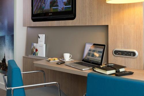a laptop computer sitting on a desk with a tv at Novotel Leuven Centrum in Leuven