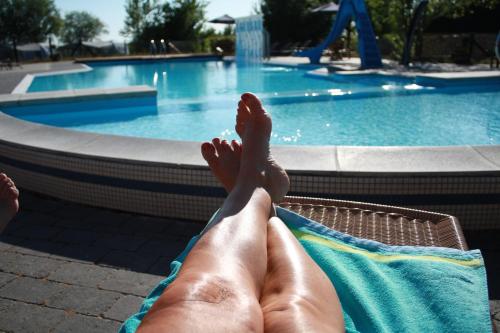 une personne assise sur une chaise en face d'une piscine dans l'établissement Vesterlyng Camping and Cottages, à Føllenslev