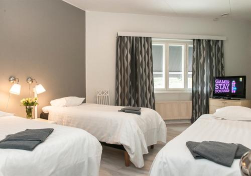 um quarto de hotel com duas camas e uma televisão em Hotelli & Ravintola Martinhovi em Raisio