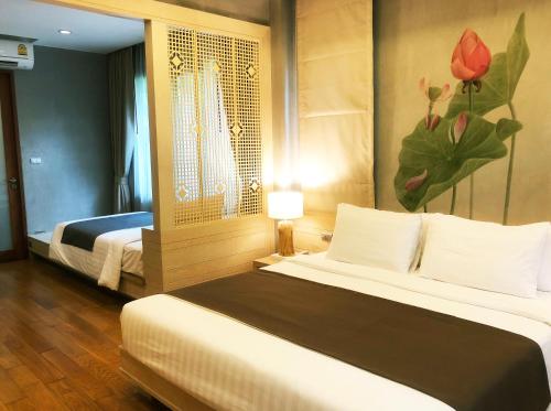 a hotel room with two beds and a painting on the wall at Chu Hotel in Chiang Mai