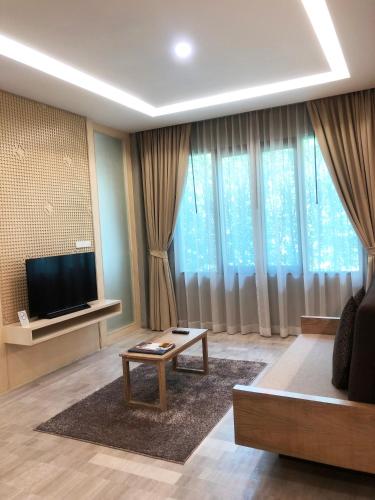 a living room with a couch and a tv and curtains at Chu Hotel in Chiang Mai