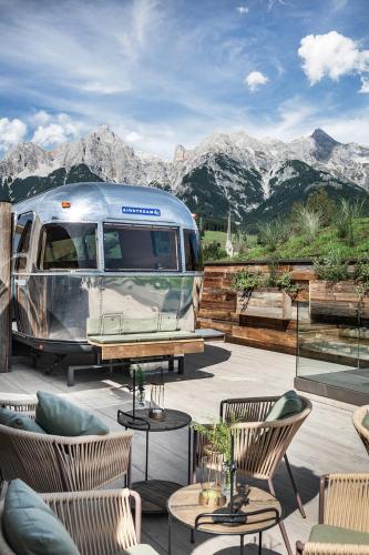 a silver airstream trailer parked on a patio with mountains at HOTEL SEPP - Alpine Boutique Hotel - Adults Only ab 21 Jahre in Maria Alm am Steinernen Meer