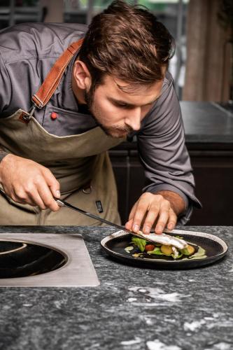 a man preparing a plate of food on a counter at HOTEL SEPP - Alpine Boutique Hotel - Adults Only ab 21 Jahre in Maria Alm am Steinernen Meer