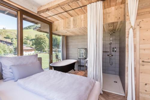 sypialnia z prysznicem, łóżkiem i oknem w obiekcie HOTEL SEPP - Alpine Boutique Hotel - Adults Only ab 21 Jahre w mieście Maria Alm am Steinernen Meer