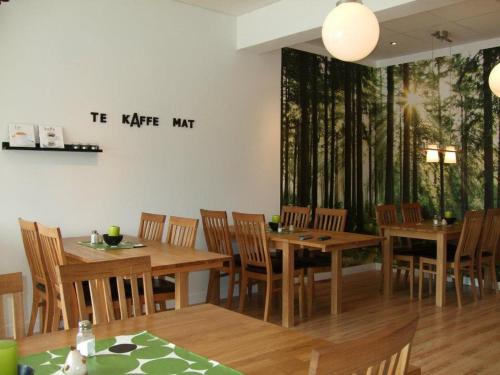 Alléhotellet في Finspång: غرفة طعام مع طاولات وكراسي خشبية