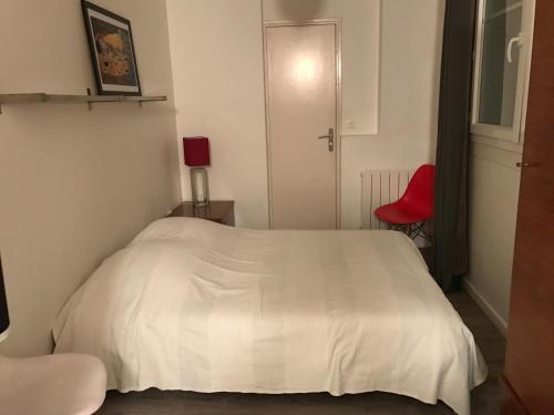 - un lit blanc dans une chambre avec une chaise rouge dans l'établissement Notre Dame de Lorette 75009 Paris, à Paris
