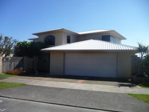 a house with two garage doors in a driveway at 49 on Jans Beach Break in Oakura