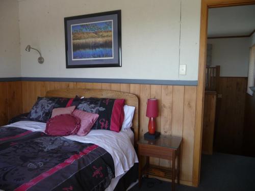 1 dormitorio con 1 cama y 1 mesa con lámpara en 49 on Jans Beach Break en Oakura