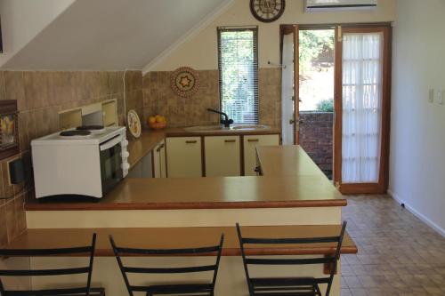 a kitchen with a counter and chairs in it at Le Residence de Josephine in Kloof