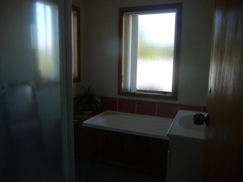 a bathroom with a bath tub and a window at 49 on Jans Beach Break in Oakura