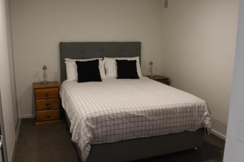 a bedroom with a large bed with black pillows at Point Lonsdale 1 Bedroom Apartment in Point Lonsdale
