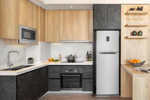 a kitchen with a white refrigerator and wooden cabinets at Somerset Norodom Phnom Penh in Phnom Penh