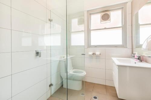 a white bathroom with a toilet and a sink at Dalziel Lodge in Sydney