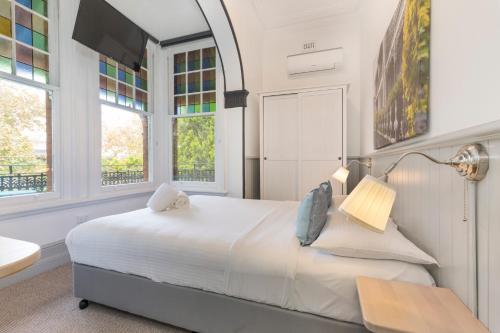 a white bedroom with a large bed and windows at Dalziel Lodge in Sydney