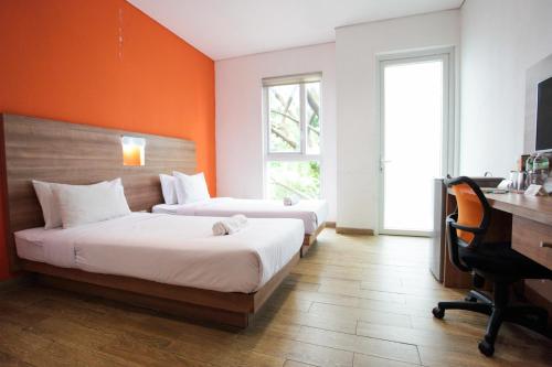 - 2 lits dans une chambre avec un mur orange dans l'établissement LeGreen Suite Kuningan, à Jakarta