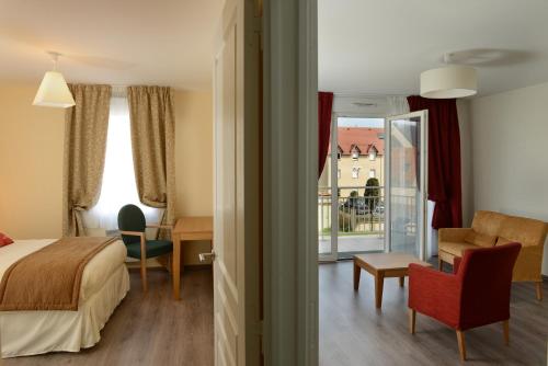um quarto de hotel com uma cama e uma varanda em Domitys La Plage de Nacre em Courseulles-sur-Mer