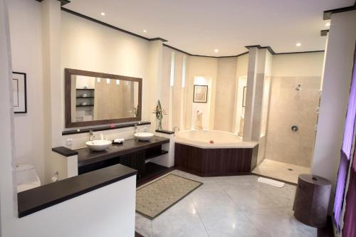 a bathroom with a tub and a sink and a bath tub at BougainVilla - Oceanfront villa with Cook, ideal for Weddings and Events in Keramas