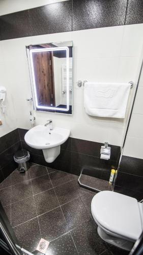 a bathroom with a sink and a toilet and a mirror at Hotel Juralius in Tbilisi City