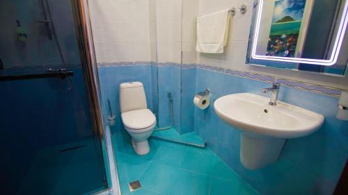 a blue bathroom with a toilet and a sink at Hotel Juralius in Tbilisi City