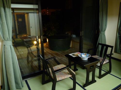 a room with a table and chairs and a tub at Kisoya in Gero