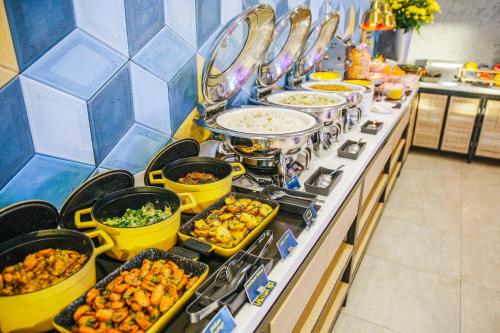 a buffet with many dishes of food on a counter at YELLO Hotel Paskal Bandung in Bandung